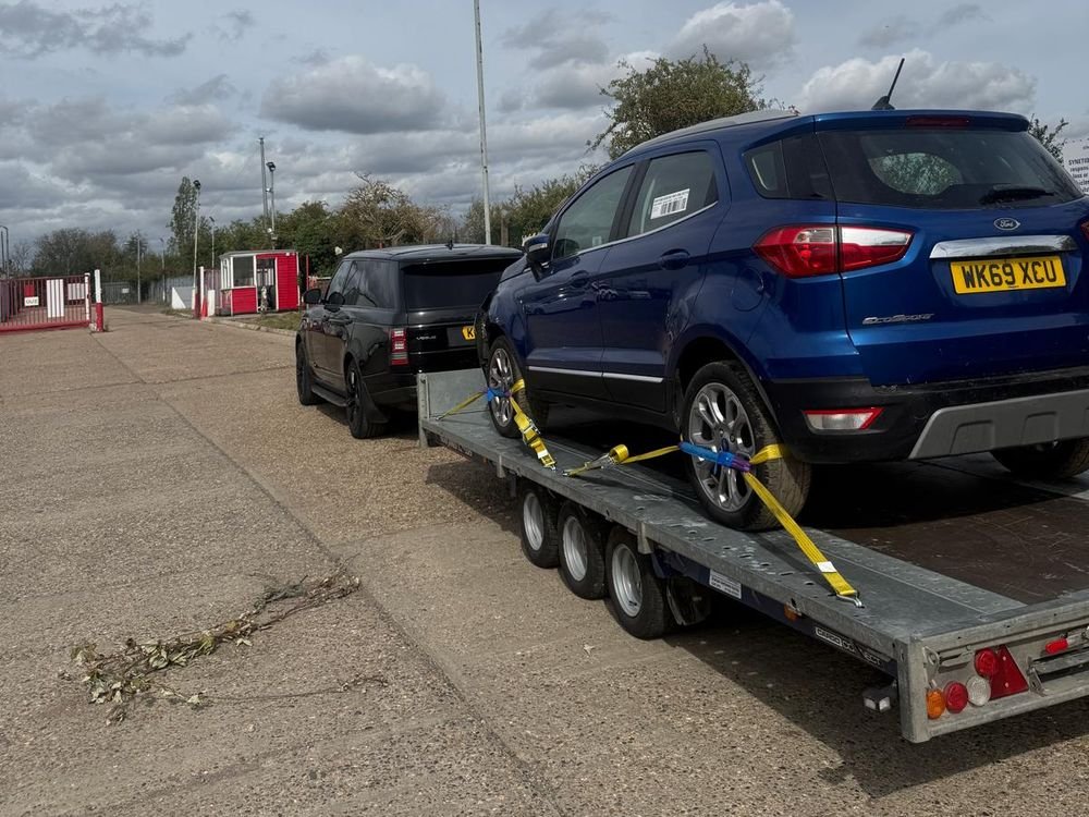 Blue Ford EcoSport strapped onto a trailer at a collection yard