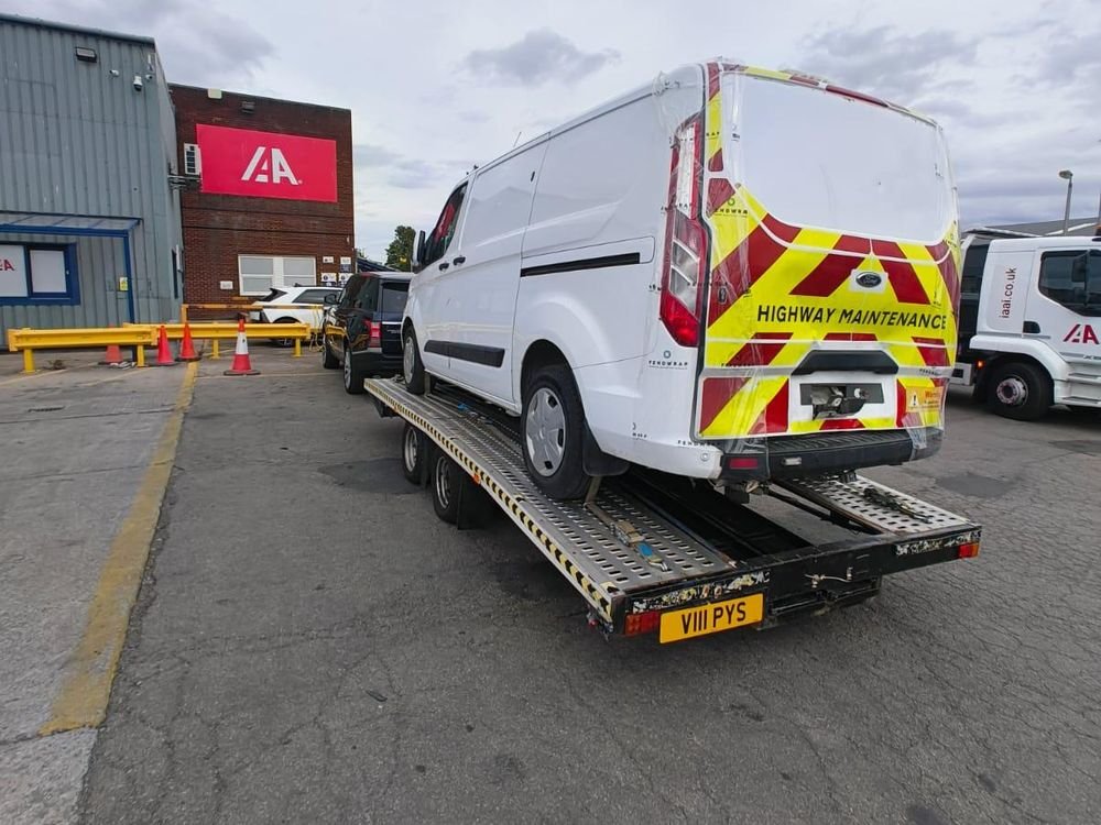 White van loaded onto a recovery trailer at an insurance auction site