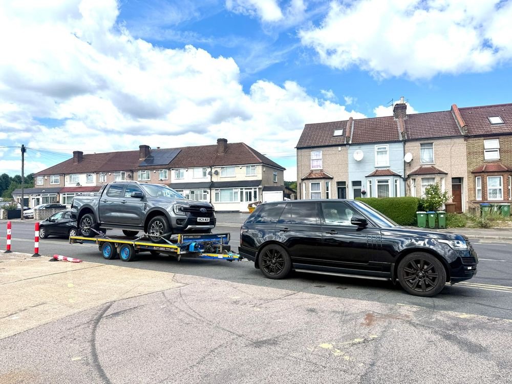 Range Rover towing a Ford Ranger on a car transporter trailer